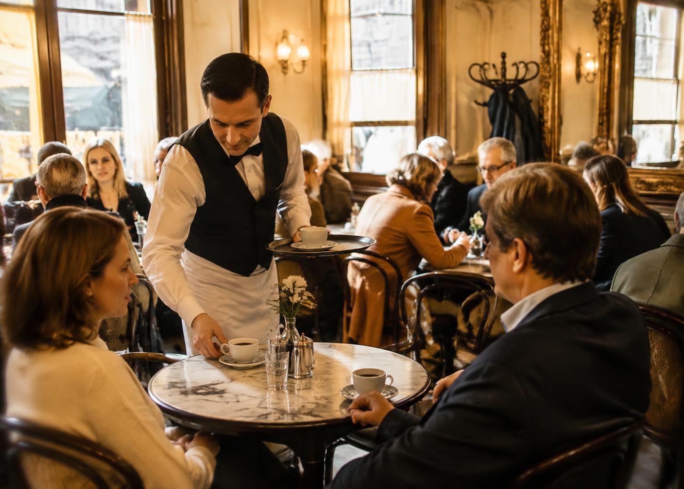 Kellner serviert Kaffee in einem klassischen Kaffeehaus